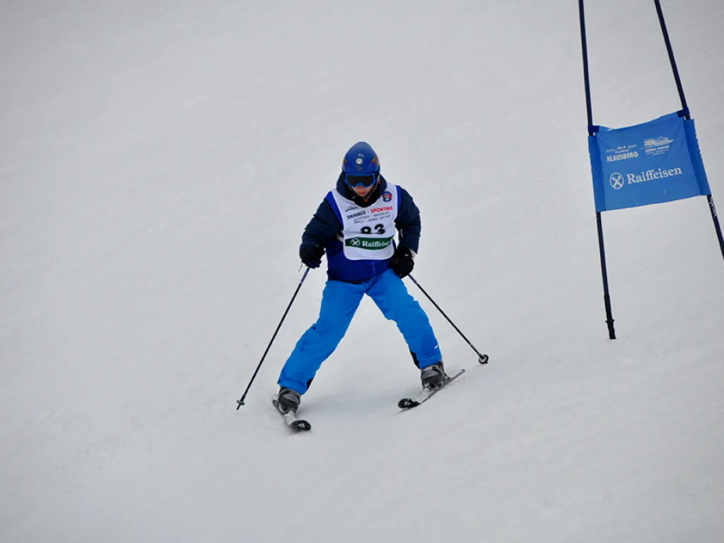 Skifahrer in blauer Kleidung neben dem blauen Tor.